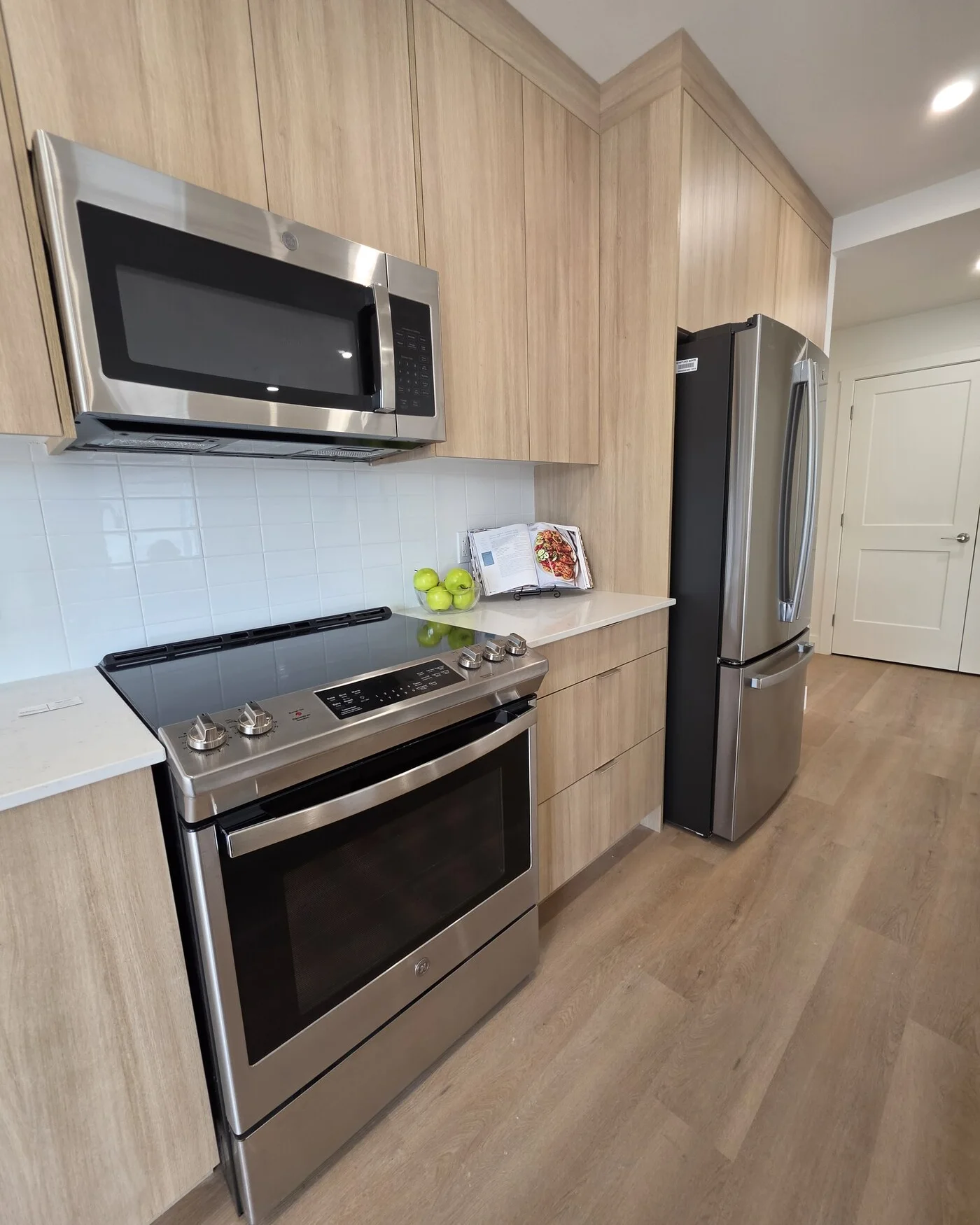 Stainless range, over-the-range microwave and French-door fridge set into floor-to-ceiling wood-grain cabinetry